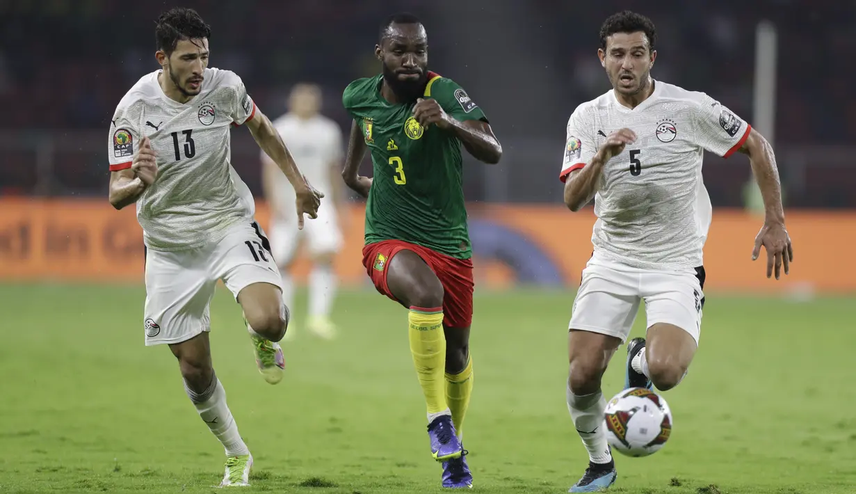 Gelandang Kamerun Moumi Ngamaleu bersaing dengan pemain Mesir Hamdi Fathi dan Ahmed Fatouh pada laga semifinal Piala Afrika 2021 di Paul Biya Stadium, Jumat (4/2/2022) dini hari WIB. Mesir sukses mengalahkan Kamerun 3-1 via drama adu penalti.  (AP Photo/Themba Hadebe)