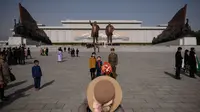 Sebuah keluarga berfoto di Mansu Hill dengan latar patung Kim Il-sung dan Kim Jong-il (AFP)