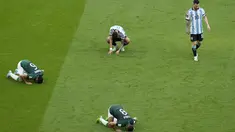 Penyerang Argentina Lionel Messi meninggalkan lapangan saat bek Arab Saudi Mohammed Al-Burayk dan rekan setimnya Abdulelha Al-Malki berselebrasi dengan cara sujud pada laga pembuka Grup C Piala Dunia 2022 Qatar di Lusail Iconic Stadium, Lusail, Selasa (22/11/2022). Argentina kalah 1-2 dari Arab Saudi. (AP Photo/Luca Bruno)
