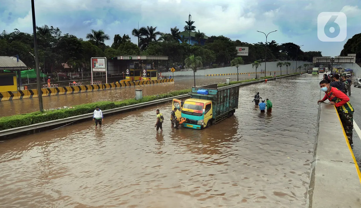 Anggota Brigif 17 Kostrad TNI AD yang kebetulan lewat bersiap mendorong truk yang mogok saat banjir menggenangi Jalan Tol JORR di kawasan TB Simatupang, Jakarta Selatan, Sabtu (20/2/2021). Banjir terjadi akibat luapan Kali Serua yang berada di pinggir  jalan tol. (merdeka.com/Arie Basuki)