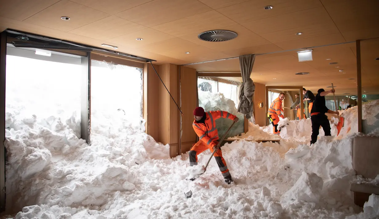 Petugas membersihkan longsoran salju yang masuk ke dalam Hotel Saentis di Schwaegalp, Swiss, Jumat (11/1). Longsoran salju nyaris mengubur Hotel Saentis. (Gian Ehrenzeller/Keystone via AP)