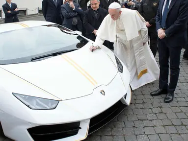 Paus Fransiskus memberikan tanda tangan di kap mesin Lamborghini Huracan di Vatikan, Rabu (15/11). Perusahaan Lamborghini memberi hadiah mobil Lamborghini Huracan berwarna putih untuk Paus Fransiskus. (L'Osservatore Romano/Pool Photo via AP)