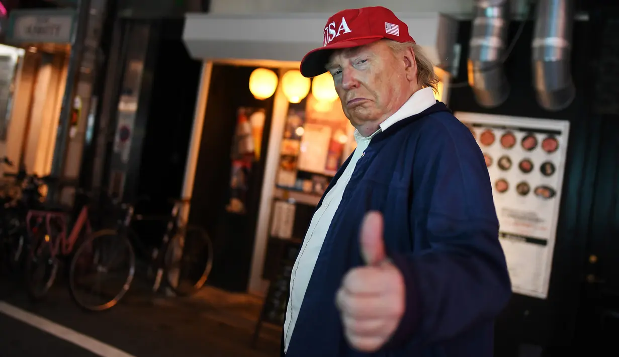 Peniru Presiden AS, Donald Trump mengacungkan jempol ketika berjalan-jalan selama gelaran KTT G20 di Osaka, Jepang, Jumat (28/6/2019). Sejumlah pemimpin dunia berkumpul dalam KTT G20 yang berlangsung dua hari di Osaka. (Charly TRIBALLEAU/AFP)