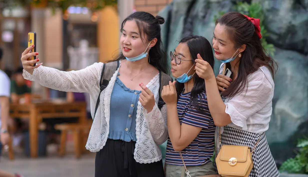 Para wisatawan berfoto saat mengunjungi Grand Bazaar Food Street di Urumqi, ibu kota Daerah Otonom Uighur Xinjiang, China barat laut, pada 4 Juli 2020. (Xinhua/Zhao Ge)