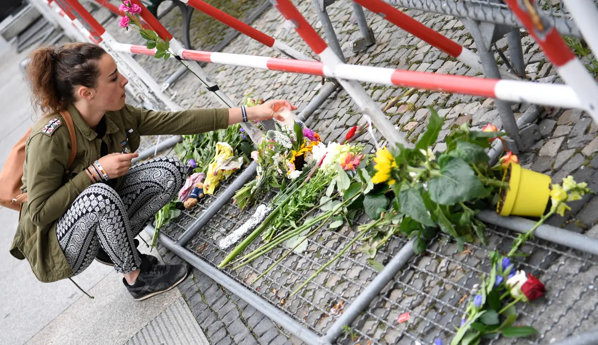 Seorang wanita meletakkan bunga di depan Kedutaan Besar Perancis di Berlin, Jerman (15/7). Karangan bunga tersebut untuk menghormati para korban teror Truk Maut saat perayaan hari Bastille di Nice. (AFP PHOTO/John MacDougall)