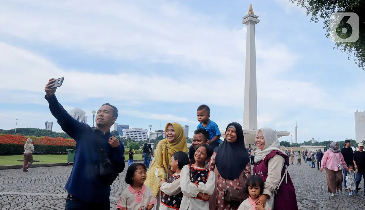 Warga berswafoto saat berwisata di kawasan Monumen Nasional (Monas), Jakarta, Sabtu (5/4/2025). (Liputan6.com/Herman Zakharia)