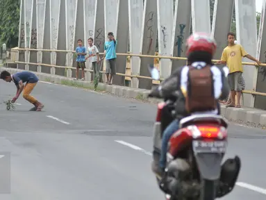 Seorang bocah mengambil uang yang dilempar pengguna jalan di Jembatan Cikalong, Jawa Barat, Sabtu (2/7). Memasuki mudik Lebaran, jumlah pencari uang sedekah di kawasan itu meningkat dibanding hari biasa (Liputan6.com/Gempur M Surya)