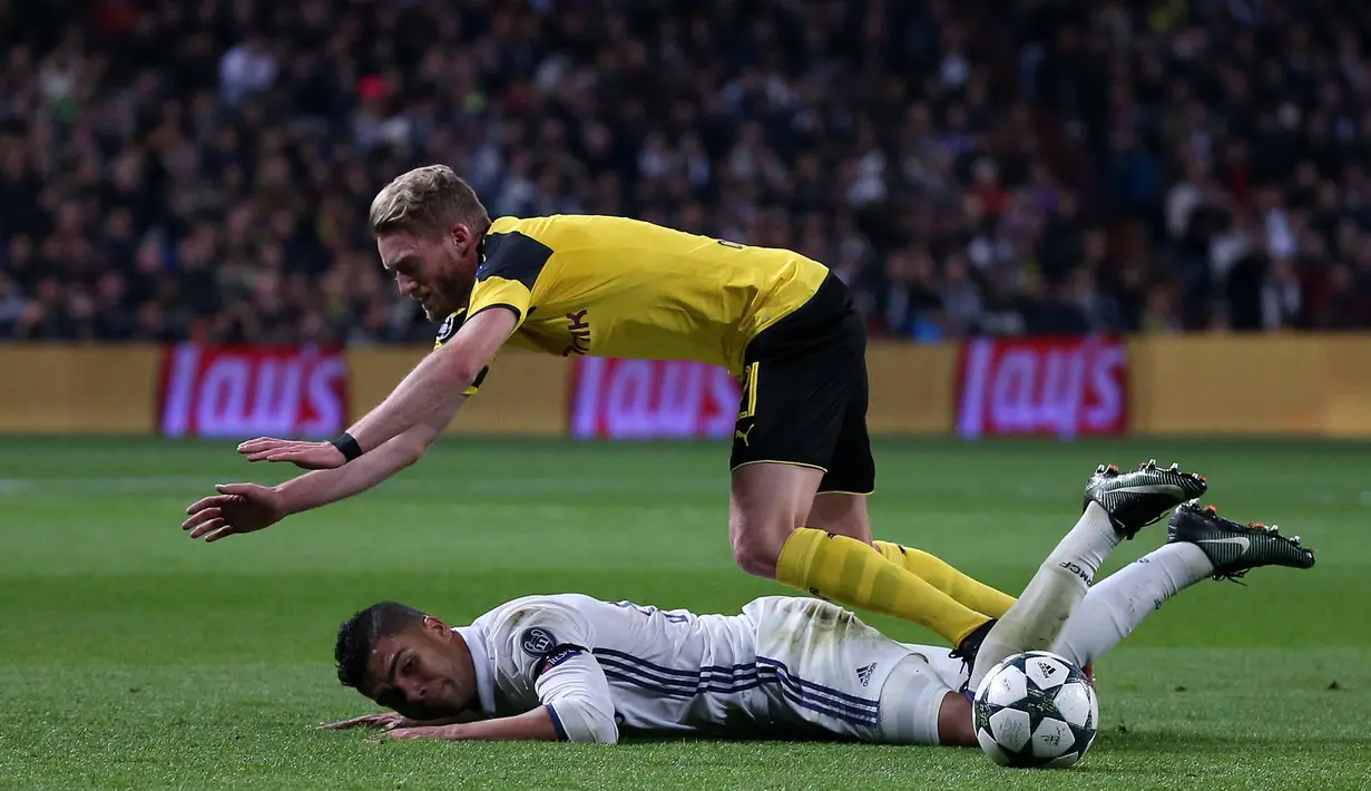 Penyerang Dortmund, Andre Schurrle terjatuh dari kawalan gelandang Real Madrid, Casemiro pada pertandingan Grup F Liga Champions di Santiago Bernabeu, Madrid, (8/12). Real Madrid bermain imbang 2-2 dengan Dortmund. (REUTERS/Juan Medina)