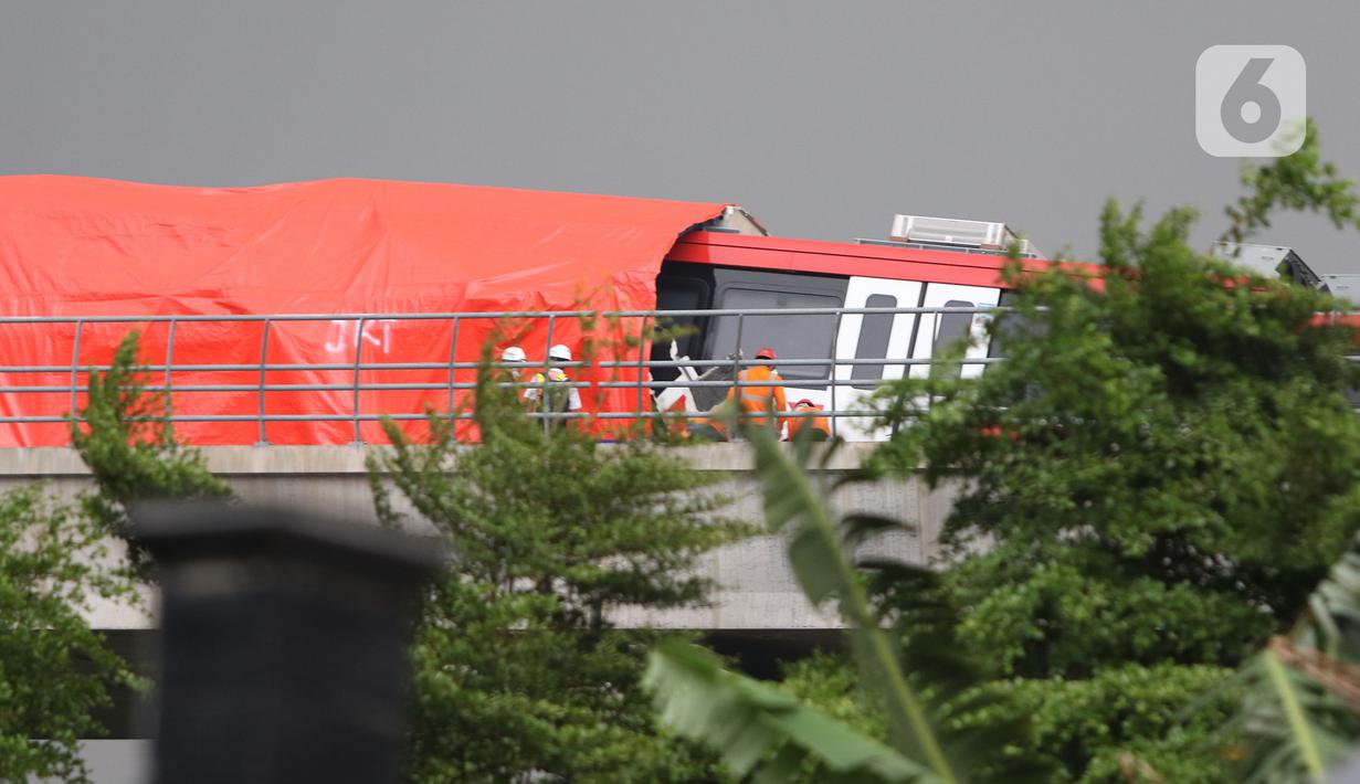 Petugas mengecek kereta ringan lintas rel terpadu (LRT) Jabodebek yang mengalami kecelakaan di jalur lintas LRT Cibubur, Jakarta Timur, Senin (25/10/2021). Petugas terlihat ada di rel untuk membantu proses evakuasi di mana bagian gerbong kereta ditutup terpal. (Liputan6.com/Herman Zakharia)