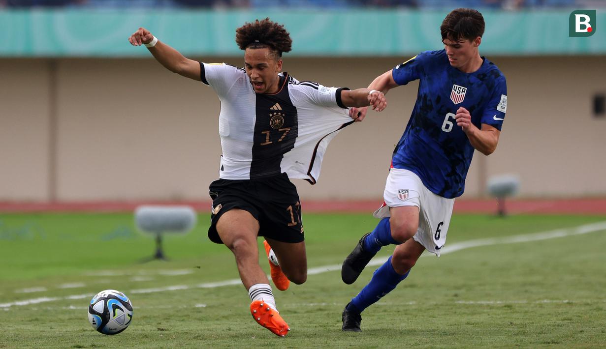 Pemain Timnas Jerman U-17, Eric Da Silva Moreira (kiri) berbut bola dengan pemain Timnas Amerika Serikat U-17, Matthew Corcoran pada laga 16 besar Piala Dunia U-17 2023 yang berlangsung di Si Jalak Harupat, Bandung, Selasa (21/11/2023). (Bola.com/Ikhwan Yanuar)