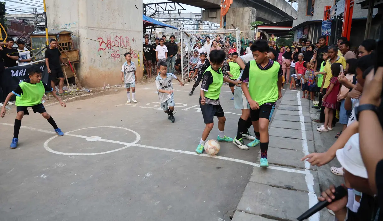 Anak-anak mengikuti pertandingan Turnamen Sepak Bola Liga Aspal U-13 di kawasan permukiman padat di pinggir rel RT 09/RW 08, Menteng Jaya, Jakarta, Senin (29/6/2026). (merdeka.com/ Arie Basuki)