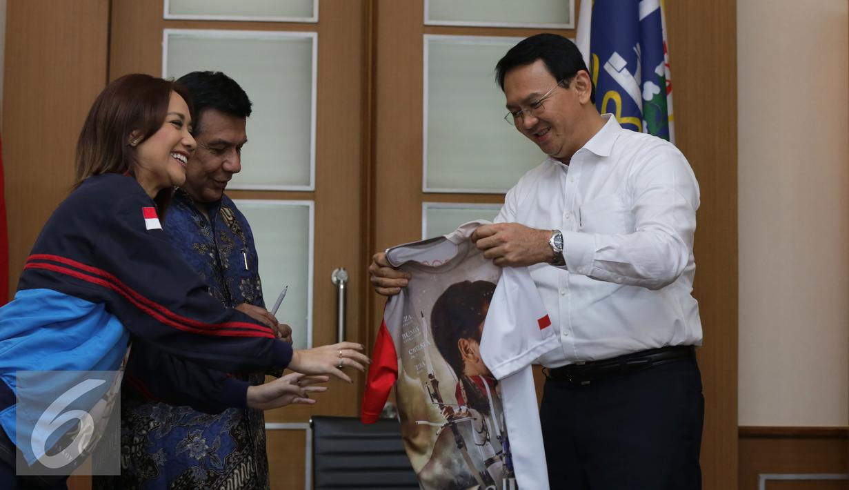 Gubernur DKI Jakarta Basuki Tjahaja Purnama menerima kaos film 3 Srikandi di Balai Kota, Jakarta, Selasa (19/7). Film 3 Srikandi melakukan promo sekaligus mengajak Ahok untuk nobar Film 3 Srikandi. (Liputan6.com/Herman Zakharia)