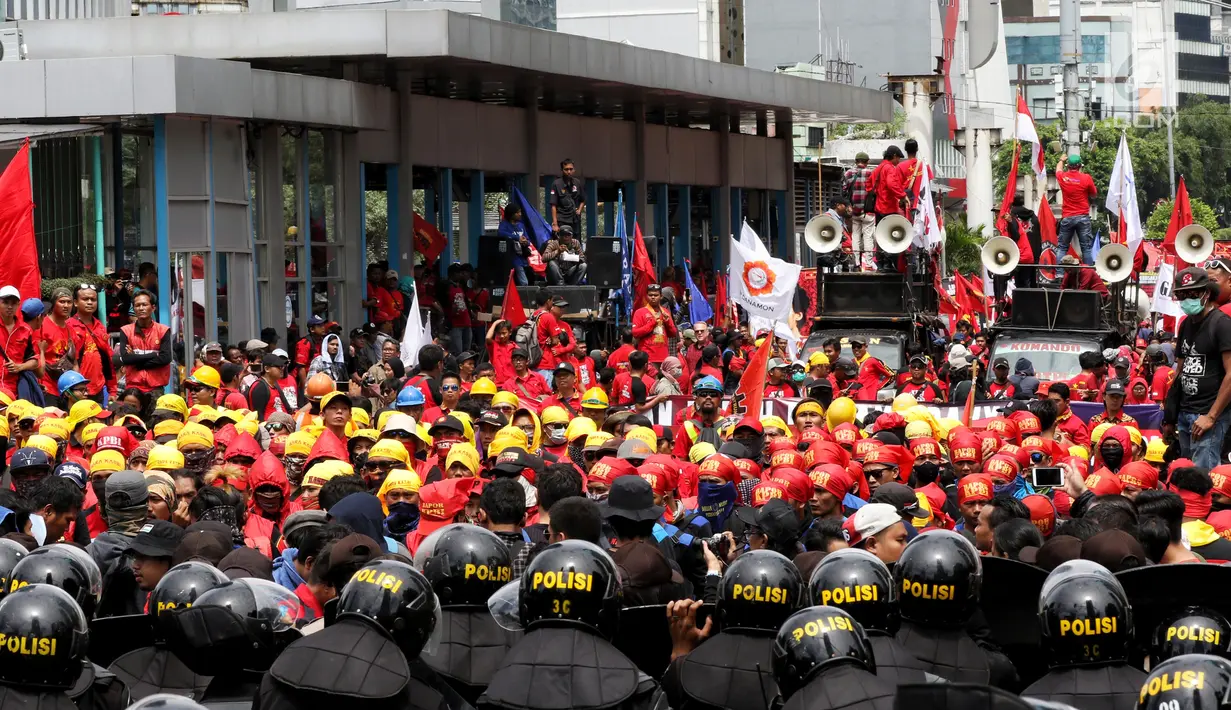 Polisi anti huru-hara menghalau para buruh saat menggelar aksi memperingati Hari Buruh Sedunia di kawasan Bundaran HI, Jakarta, Rabu (1/5/2019). Massa buruh yang hendak melakukan aksi peringatan Hari Buruh 2019  ke Istana Negara tertahan di tengah perjalanan. (Liputan6.com/Johan Tallo)