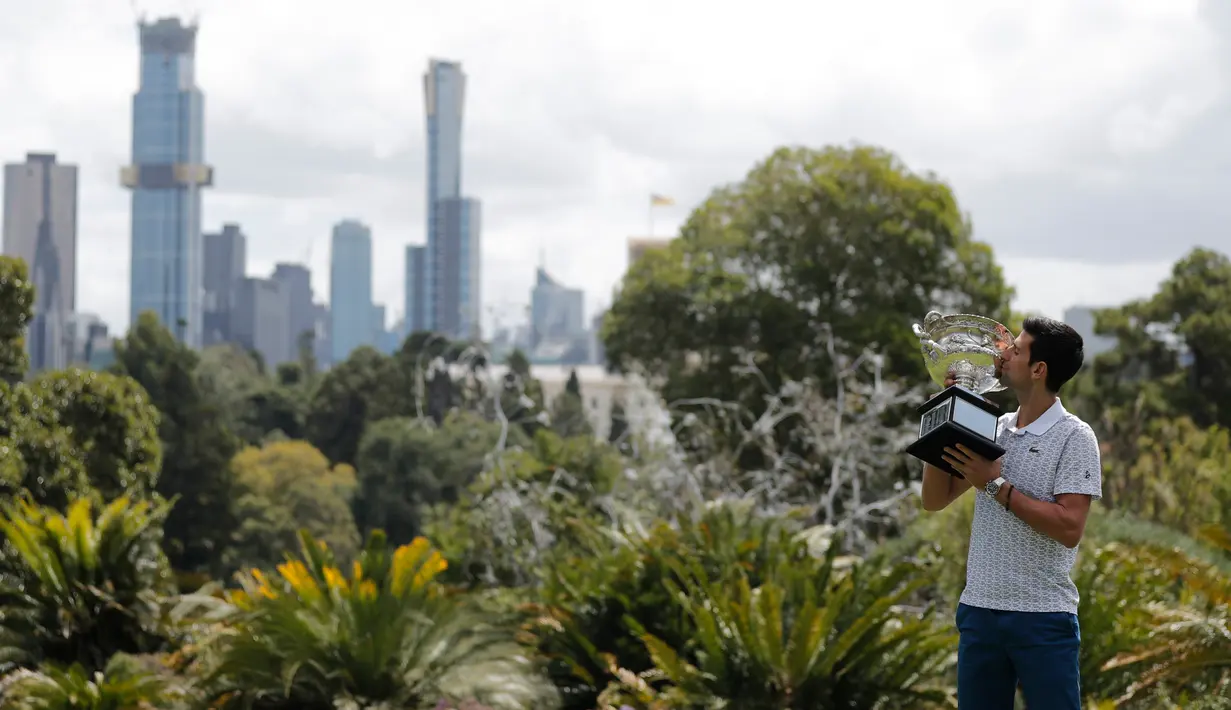 Petenis Serbia, Novak Djokovic mencium piala juara tunggal putra Australia Terbuka 2020 saat sesi pemotretan di Royal Botanic Gardens Victoria, Melbourne, Australia, Senin (3/2/2020). Djokovic sudah mengoleksi sebanyak 17 gelar grand slam dengan kemenangan kali ini. (AP Photo/Dita Alangkara)