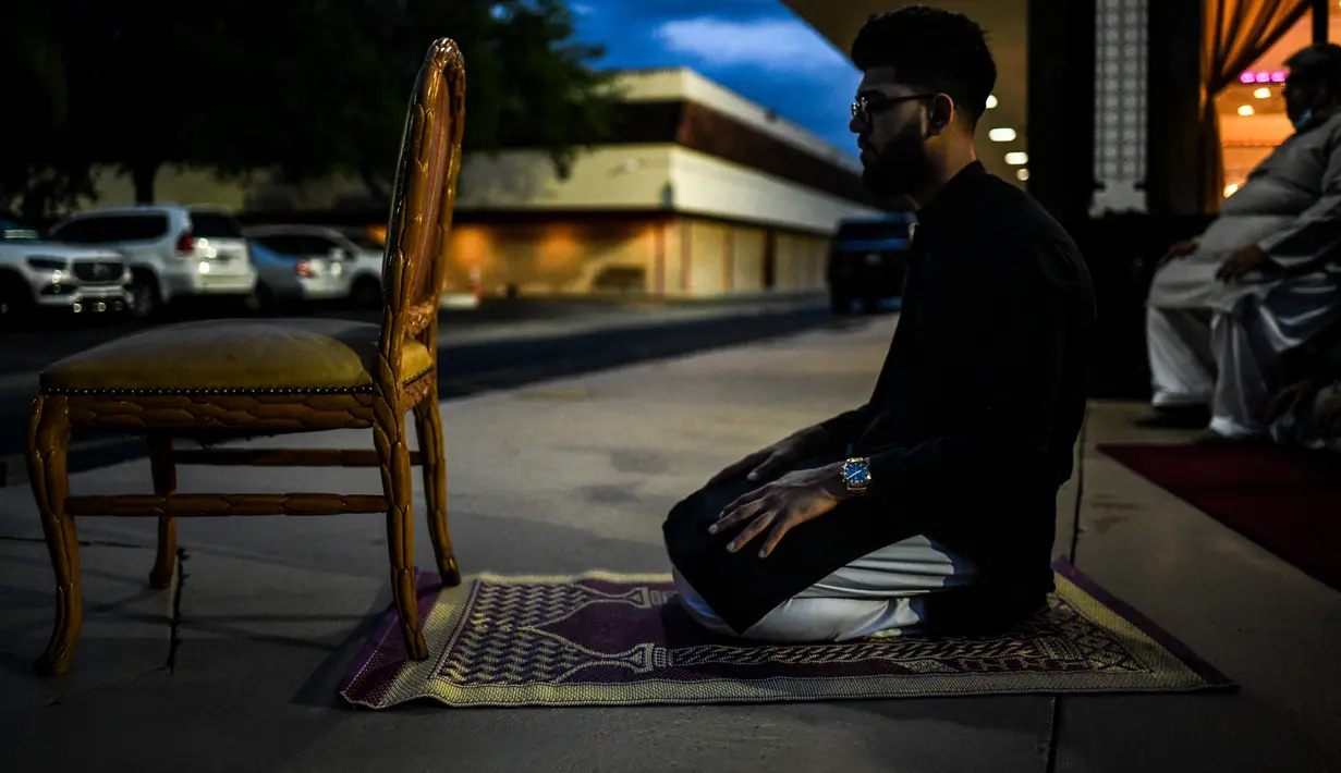 Seorang pria Muslim melaksanakan salat di trotoar di luar restoran selama bulan suci Ramadhan di Lauderhill, Florida, Jumat (30/4/2021). Selama puasa Ramadhan, umat Islam tidak makan, minum, atau aktivitas seksual dari fajar hingga matahari terbenam. (CHANDAN KHANNA/AFP)