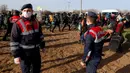Para migran melewati polisi Turki dekat perbatasan Turki dengan Yunani di Gerbang Pazarkule, Edirne, Turki, Selasa(3/3/2020). (AP Photo/Darko Bandic)