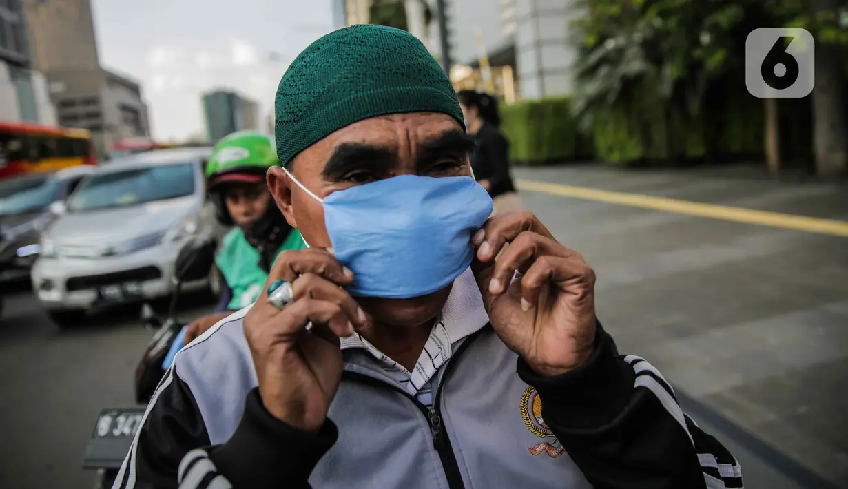 Warga mengenakan masker yang dibagikan relawan di Bundaran HI, Jakarta, Selasa (17/3/2020). Sebanyak 3.000 masker dibagikan gratis kepada pengguna jalan sebagai salah satu bentuk keprihatinan sekaligus berpartisipasi dalam upaya mencegah penyebaran virus corona COVID-19. (Liputan6.com/Faizal Fanani)