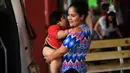 Isabel Pantoja  menggendong anaknya Luis Gonzales saat menunggu di stasiun bus di Tecoman, negara bagian Colima, Meksiko (9/11). (AFP Photo/Pedro Pardo)