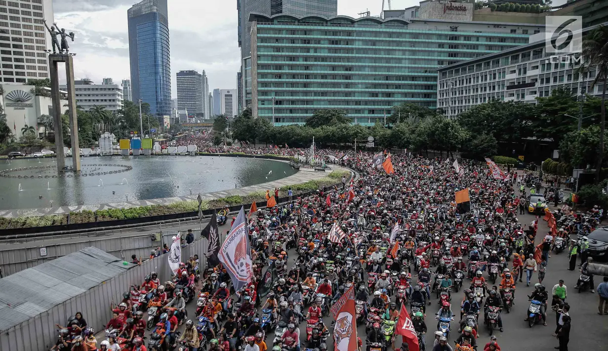Ratusan sepeda motor suporter Persija Jakarta, Jakmania, melakukan pawai kemenangan Juara Piala Presiden di kawasan Bundaran HI, Minggu (18/2). Konvoi arak-arakan dimulai dari Stadion Utama Gelora Bung Karno menuju Balai Kota. (Liputan6.com/Faizal Fanani)