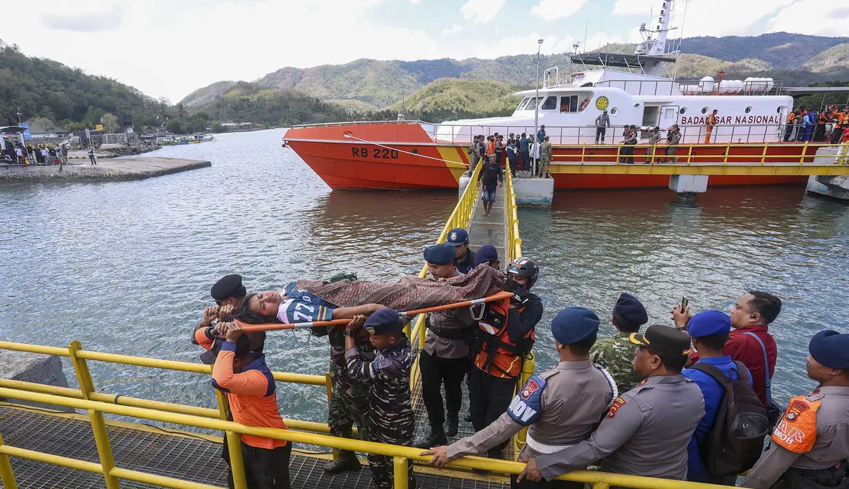 Petugas penyelamat, personel militer, dan polisi membawa penumpang yang telah dievakuasi menggunakan tandu turun dari kapal pencarian dan penyelamatan di Pelabuhan Lembar, Lombok Barat, Rabu, 12 Agustus 2026. (AFP)