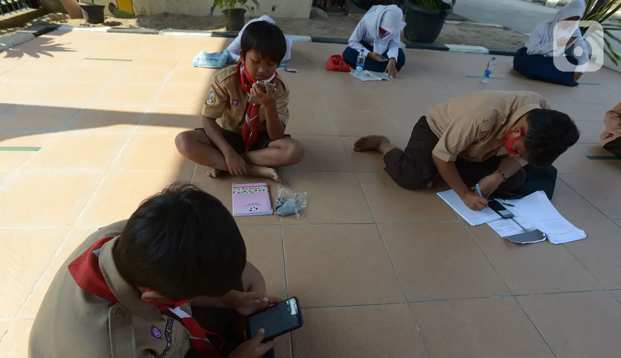 Para siswa belajar di kolong rel kereta api Mangga Besar, Jakarta,Rabu (19/8/2020). Proses belajar siswa tersebut menggunakan modem paket internet wifi gratis yang disediakan untuk mengikuti pembelajaran jarak jauh. (merdeka.com/Imam Buhori)
