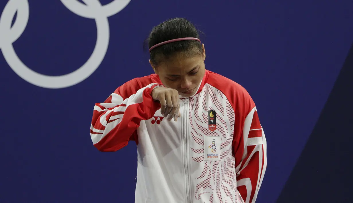 Lifter Lisa Setiawati menangis saat naik podium usai mendapatkan medali perak SEA Games 2019 cabang angkat besi nomor 45 kg di Stadion Rizal Memorial, Manila, Minggu (1/12). Dirinya meraih perak dengan total angkatan 169 kg. (Bola.com/M Iqbal Ichsan)