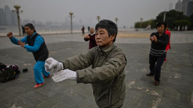Orang-orang berlatih tai chi di pagi hari di sebelah Sungai Yangtze di Wuhan (20/11/2020). Dari total 50.340 kasus yang positif di Wuhan, 3.869 orang telah meninggal dunia akibat Covid-19 dan yang sembuh 46.471 orang. (AFP/Hector Retamal)