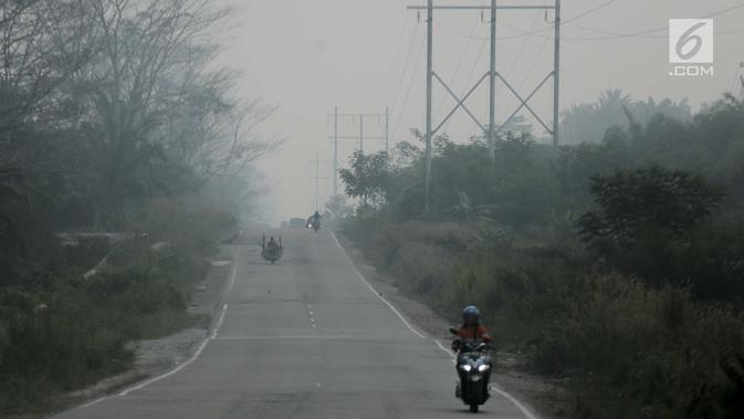 Pengendara motor menembus kabut asap pekat yang menyelimuti Kota Pekanbaru, Riau, Selasa (10/9/2019). Kabut asap akibat kebakaran hutan dan lahan (karhutla) tersebut menurunkan jarak pandang dan kualitas udara turun ke status tidak sehat. (Liputan6.com/Faizal Fanani)