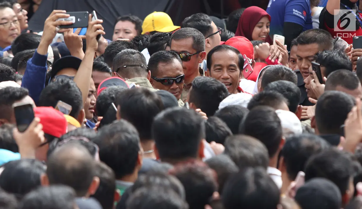 Presiden Joko Widodo (tengah) berjalan menembus kerumunan warga usai peresmian pengoperasian Moda Raya Terpadu Jakarta fase 1 di Kawasan Bundaran HI, Jakarta, Minggu (24/3). Acara ini sekaligus pencanangan pembangunan Moda Raya Terpadu Jakarta fase 2. (Liputan6.com/Helmi Fithriansyah)