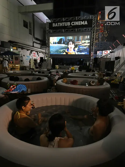 Pengunjung menonton film sambil berendam di Bathtub Cinema di atap gedung Shibuya, Tokyo, 17 Agustus 2018. Acara yang digelar selama tiga hari pada Agustus ini menyajikan film, Jumanji: Welcome to the Jungle, Baby Driver dan Spider Man (AFP/Kazuhiro NOGI)