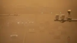Kendaraan melintas di tengah badai pasir pada jam sibuk pagi hari di Beijing, Senin (15/3/2021). Badan Meteorologi China mengumumkan status kuning dengan menyatakan, badai pasir telah menyebar dari Mongolia ke Provinsi Gansu, Shanxi, dan Hebei, di sekitar Beijing. (AP Photo/Mark Schiefelbein)
