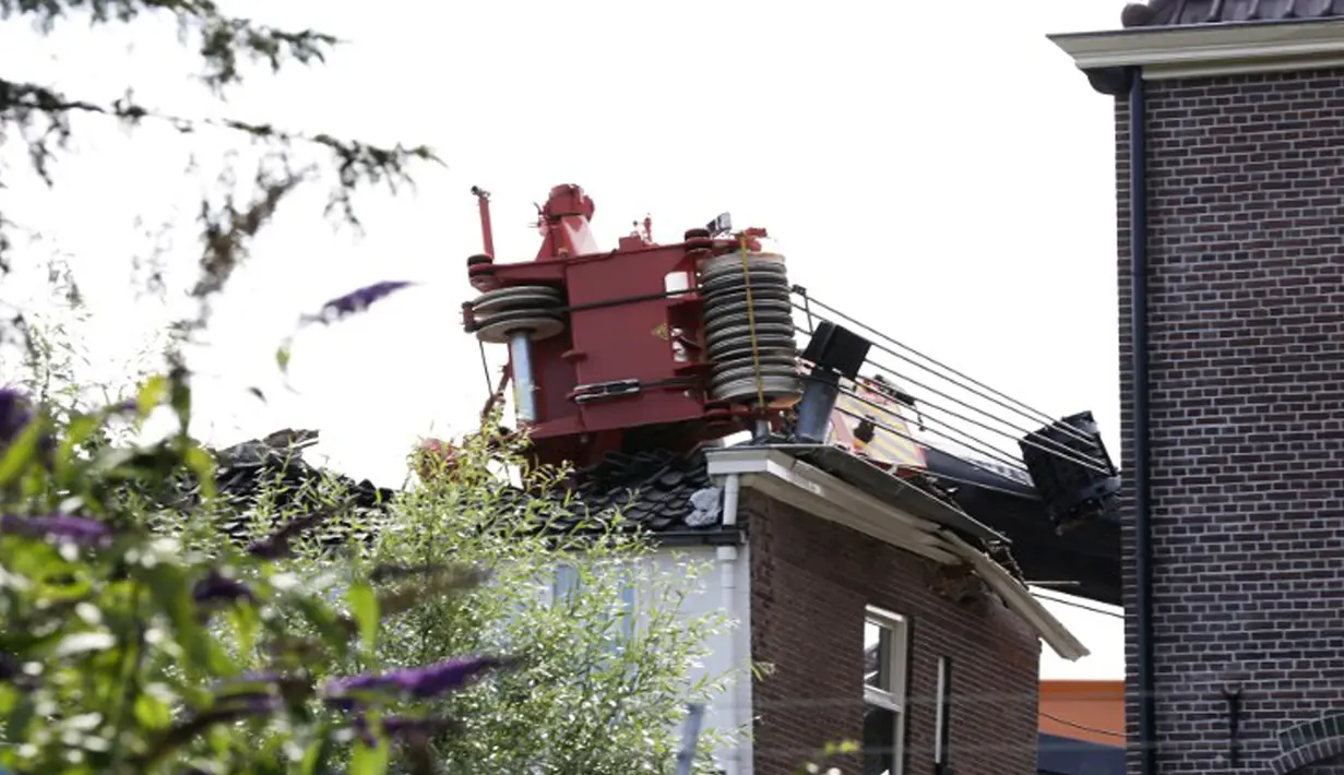 Salah satu mesin derek yang jatuh ke rumah warga di Alphen aan den Rijn, Belanda, Senin (3/8/2015) waktu setempat. Dua mesin derek yang sedang memperbaiki jembatan ambruk ke rumah yang ada di dekatnya dan melukai 20 orang. (AFP PHOTO/ANP/LEX VAN LIESHOUT)