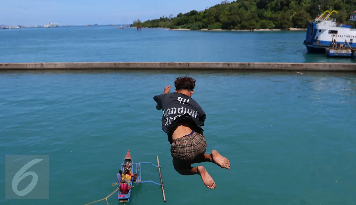 Seorang anak melompat ke laut ketika penumpang melemparkan koin dari atas kapal di Pelabuhan Merak, Banten, Jumat (26/8). Aksi anak-anak pemburu koin itu menjadi hiburan bagi penumpang yang akan menyeberang ke Pulau Sumatera. (Liputan6.com/Angga Yuniar)
