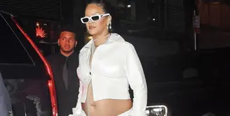 Mengenakan button down shirt dan high slit dress, aksen aksesori panjang jadi pusat perhatian gaya Rihanna di ajang after party. [Foto: Instagram/ Whowhatwear]