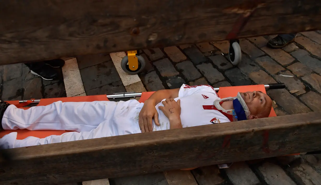 Seorang peserta ditandu tim medis setelah diseruduk banteng dalam Festival San Fermin di Pamplona, Spanyol utara, (9/7). Ratusan orang dari seluruh dunia  setiap tahunnya ambil bagian dalam Festival Adu Banteng, San Fermin. (AP Photo/Alvaro Barrientos)