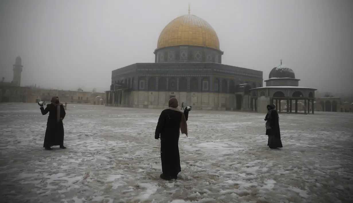 Wanita bertanding bola salju di dekat the Dome of the Rock atau Kubah Batu di kompleks Masjid Al Aqsa pada pagi bersalju di Kota Tua Yerusalem (18/2/2021). (AP Photo/Mahmoud Illean)