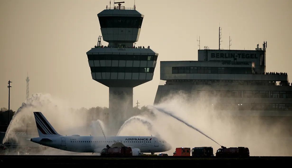 Petugas damkar menyemprotkan air di atas pesawat maskapai Air France sebagai perpisahan sebelum lepas landas dari bandara Tegel (TXL) di Berlin, Jerman, Minggu (8/11/2020). Maskapai Air France menjadi penerbangan terakhir dari Bandara Tegel yang ditutup selamanya. (Michael Kappeler/dpa via AP)