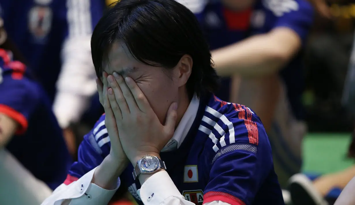 Salah satu suporter di Tokyo menutup wajah menahan kesedihan usai menyaksikan kegagalan Timnas Jepang menembus zona 16 Piala Dunia 2014, (25/6/2014). (REUTERS/Issei Kato) 