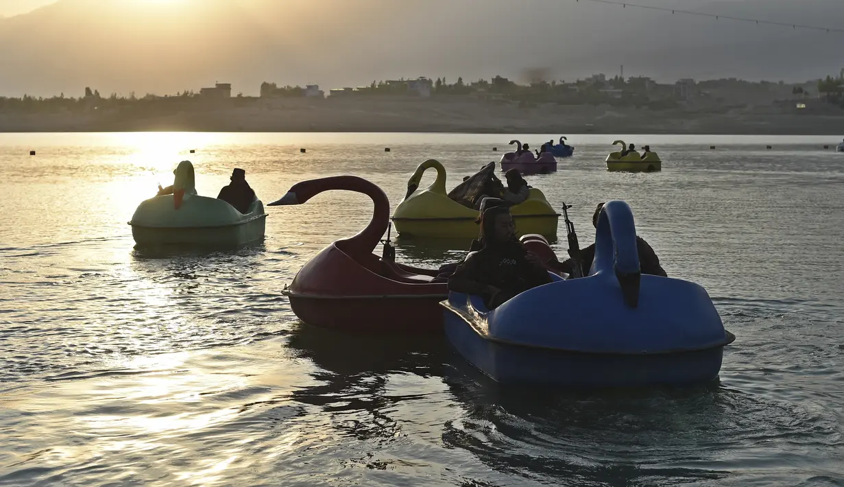Sejumlah pasukan Taliban menaiki perahu kayuh memutari Danau Qargha di sebuah pekan raya di Kabul barat (28/9/2021). Mereka menikmati waktu luangnya dengan bermain perahu kayuh di danau tersebut. (AFP/Wakil Kohsar)