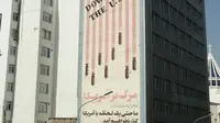 Kendaraan melintasi mural yang menggambarkan bendera Amerika Serikat (AS) di sepanjang dinding bekas Kedutaan AS di Ibu Kota Teheran, Iran, Sabtu (22/6/2019). (ATTA KENARE/AFP)