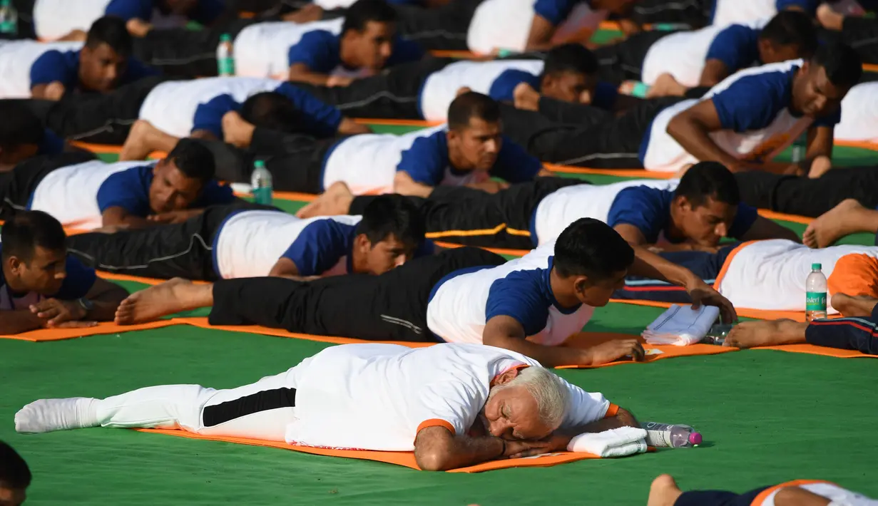 Perdana Menteri India, Narendra Modi berpartisipasi dalam sesi yoga massal pada Hari Yoga Internasional di Dehradun, Kamis (21/6). Modi melakukan gerakan peregangan, membungkuk, dan latihan pernapasan bersama praktisi yoga lainnya. (AFP/PRAKASH SINGH)