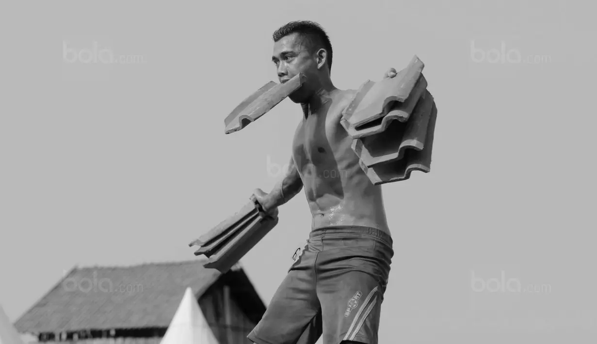 Peserta menunjukan keahliannya mengangkat genteng saat mengikuti kontes binaraga di Desa Jatiwangi, Majalengka, Jawa Barat, (11/8/2017). Kontes yang digelar setiap tahun ini merupakan bagian dari perayaan HUT kemerdekaan RI. (Bola.com/M iqbal Ichsan)