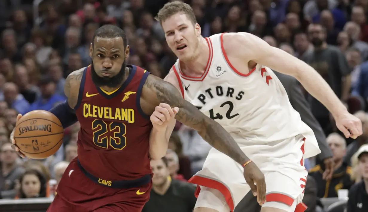 LeBron James (23) berusaha melewati adangan pemain Toronto Raptors, Jakob Poeltl (42) pada lanjutan NBA basketball game di Quicken Loans Arena, (21/3/2018) Cleveland. Cavs menang 132-129. (AP/Tony Dejak)
