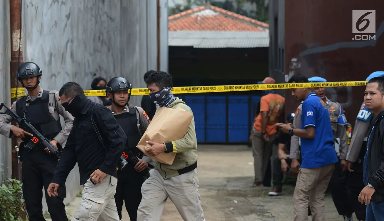Polisi bersenjata berjaga-jaga saat berlangsungnya olah TKP di rumah terduga teroris di Nanggewer, Cibinong, Bogor, Jawa Barat, Sabtu (18/5/2019). Polisi masih memasang garis kuning di gang menuju rumah terduga teroris E alias Abu Rafi alias Pak Jenggot (51). (merdeka.com/Imam Buhori)
