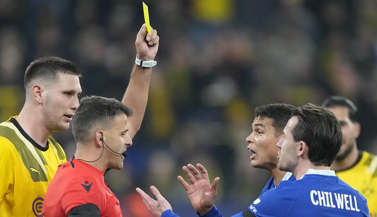 Wasit Jesus Jil Manzano memberikan kartu kuning kepada pemain Chelsea, Thiago Silva saat menghadapi Borussia Dortmund dalam laga leg pertama babak 16 besar Liga Champions 2022/2023 di Signal Iduna Park, Dortmund, Kamis (16/2/2023) dini hari WIB. (AP Photo/Martin Meissner)