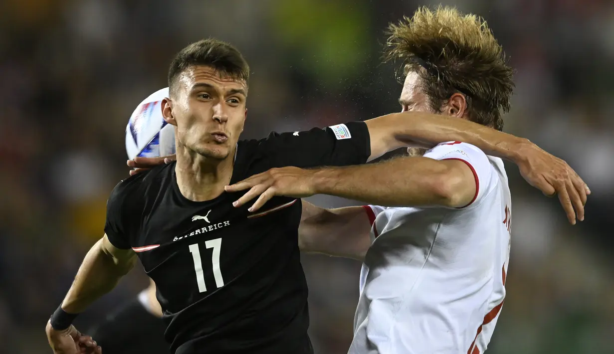 Gelandang Austria, Dejan Ljubicic berebut bola dengan pemain Denmark, Joachim Andersen pada pertandingan UEFA Nations League di Stadion Ernst Happel di Wina, Austria, Selasa (7/6/2022). Denmark menang tipis atas Austria 2-1. (AP Photo/Andreas Schaad)