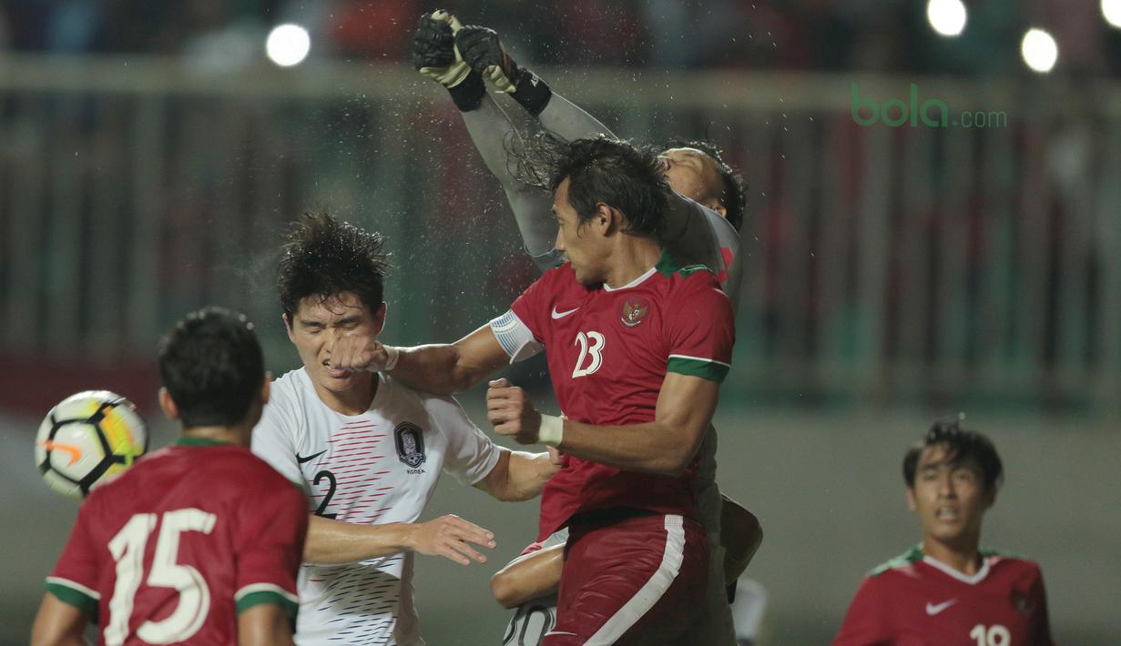 Kiper Timnas Indonesia, Awan Seto (kanan) menghalau bola dari kejaran pemain Korea Selatan U-23 pada laga uji coba di Stadion Pakansari, Bogor, (23/6/2018).  Indonesia U-23 kalah 1-2 dari Korea U-23. (Bola.com/Nick Hanoatubun)