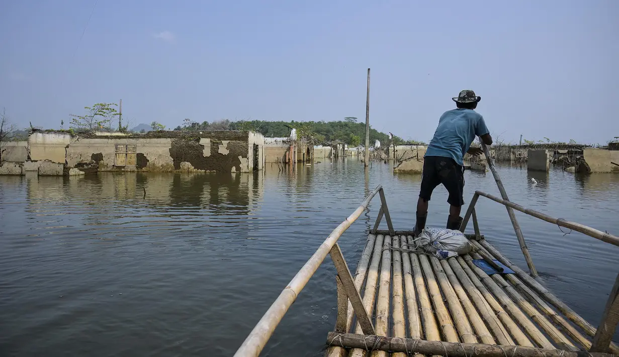 Seorang pria mengendalikan rakit bambunya di kawasan Bendungan Karian yang mengering di Kampung Somang, Lebak, Banten, Kamis (30/7/2026). (AFP/ Bay Ismoyo)