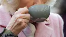 Duchess of Cornwall, Camilla Parker Bowles menikmati teh ketika mengunjungi Swiss Cottage Farmers Market di London utara, Rabu (6/11/2019). Kunjungan Pangeran Charles dan Camila untuk mengucapkan selamat dan memperingati ulang tahun ke-20 pasar tersebut. (Eddie Mulholland / POOL / AFP)