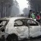 Polisi berdiri di dekat sebuah mobil yang terbakar di sebuah jalan antara Castanheira de Pera dan Figueiro dos Vinhos, Portugal tengah, 18 Juni 2017 (AFP)